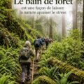 Femme se relaxant en forêt pendant un bain de forêt, entourée d'arbres, symbole de bien-être.
