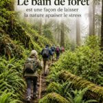 Femme se relaxant en forêt pendant un bain de forêt, entourée d'arbres, symbole de bien-être.