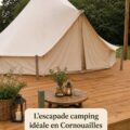 Vue d'un camping en pleine nature à Cornwall avec des tentes et le paysage côtier en arrière-plan.
